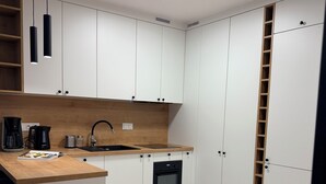 A modern kitchen with white cabinets, a wooden countertop, a built-in oven, and pendant lights. - Modern Apartment PKiN Best Location (Warsaw)