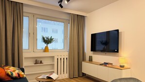A modern living room with a sofa, a small table, a TV, and a lamp. - Modern Apartment PKiN Best Location (Warsaw)