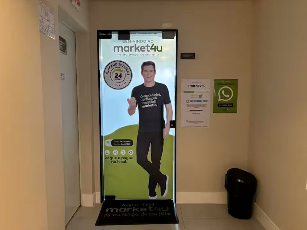 A hallway with a digital advertisement for market4u, a 24-hour service, and a trash bin.