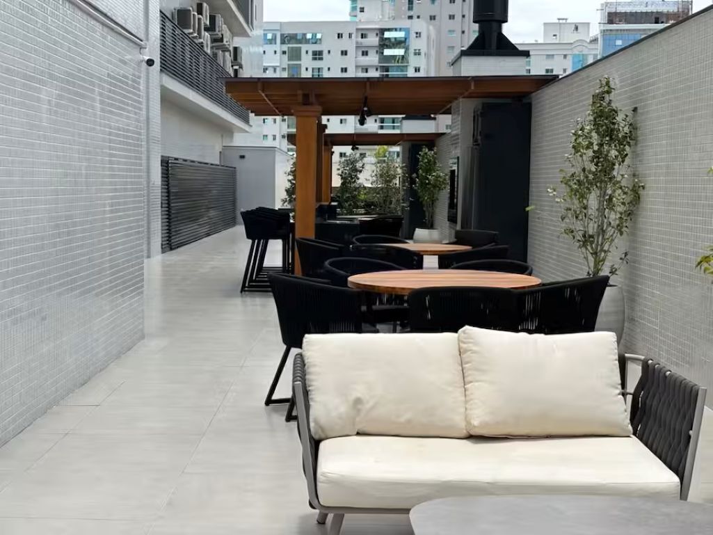 A modern outdoor patio area with a sofa, dining table, and chairs.