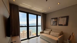 Una sala de estar moderna con un sofá, un televisor de pantalla plana y un ventanal con vistas a la ciudad.