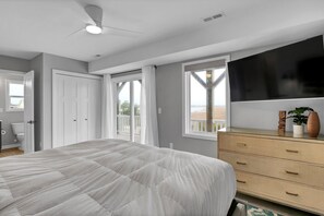 A bedroom with a bed, a dresser, a TV, and a window with a view. - Clean & Modern Home w/ 2 King Suites, Elevator, & Short Walk to Beach (Surf City)