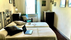 A room with a bed, a laptop, a dresser, a window, and several framed pictures on the walls. - ANCIENT HOUSE OF NEL CHIANTI FOR 10 PEOPLE (Toscana)