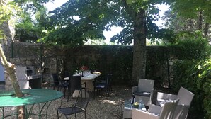 An outdoor patio with a stone wall, a table set for dining, wicker chairs, and a grill. - ANCIENT HOUSE OF NEL CHIANTI FOR 10 PEOPLE (Toscana)