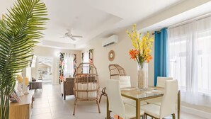 A spacious living area with a dining table, wicker chairs, a large potted plant, and a vase with flowers. - Sunshine Seashore Escape Jamaica (Lucea)