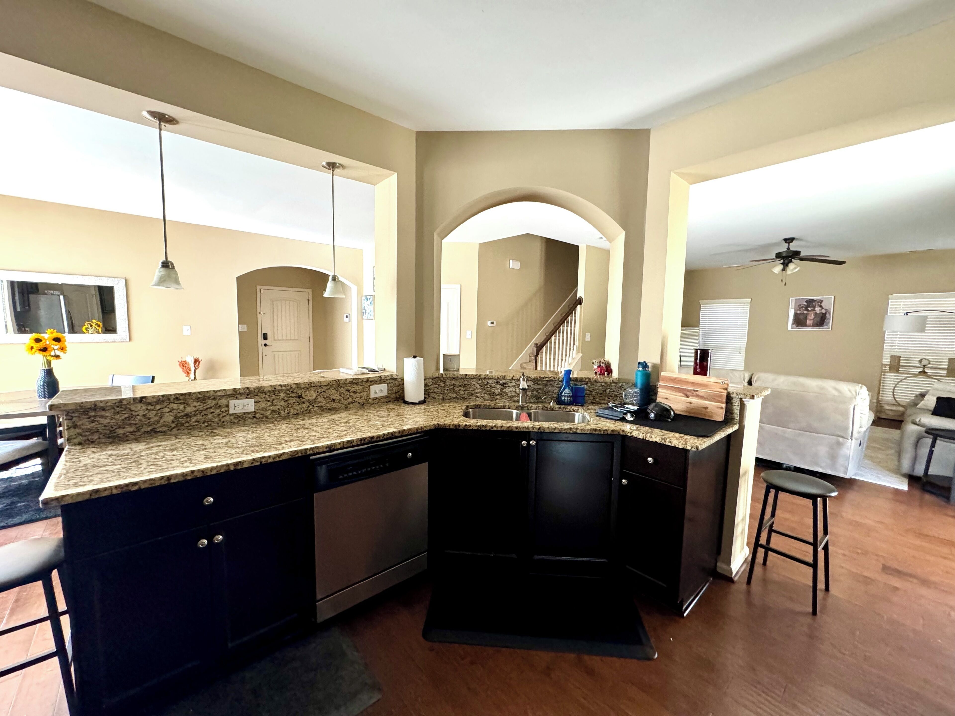 A kitchen with a granite countertop, black cabinets, a dishwasher, and a sink.