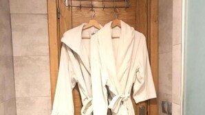 Una puerta de madera con dos túnicas blancas colgadas en un perchero.