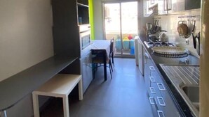 Una cocina estrecha con comedor, un banco y vistas al exterior.