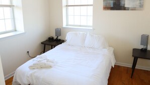 A hotel room with a bed, two bedside tables, a window, and a painting on the wall. - Beautiful 1Bed 1 Bath w/ Parking (Belleville)