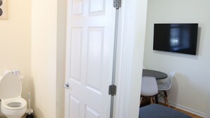 A bathroom with a toilet, a plunger, and a closed door. - Beautiful 1Bed 1 Bath w/ Parking (Belleville)