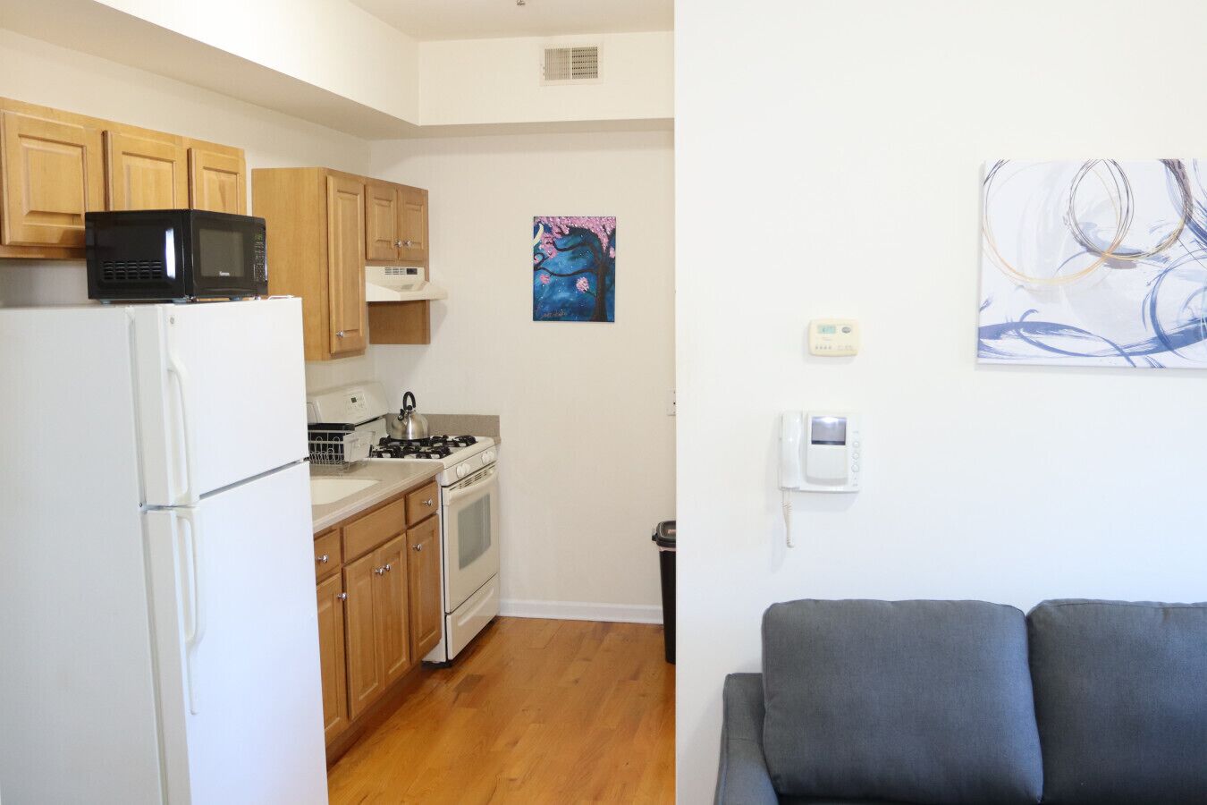 A compact kitchen with a refrigerator, stove, microwave, and wooden cabinets.