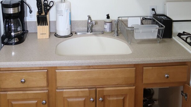 A kitchen with wooden cabinets, a sink, a coffee maker, and various kitchen utensils. - Beautiful 1Bed 1 Bath w/ Parking (Belleville)