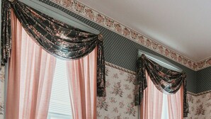 A room with a red sofa, two lamps, and floral wallpaper. - Historic District - Vintage Charm - Opal Suite (Hermann)