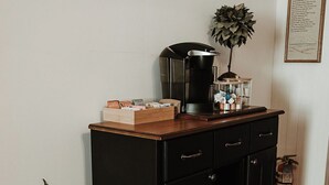 A black wooden cabinet with drawers, a coffee maker, and a small plant on top. - Historic District - Vintage Charm - Opal Suite (Hermann)
