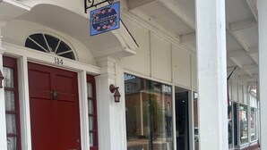 A building with a red door, a sign for Strassney Suites, and a brick entrance. - Historic District - Vintage Charm - Opal Suite (Hermann)