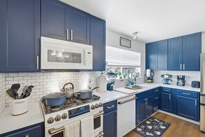 A kitchen with blue cabinets, a white microwave, a stove, and a coffee maker. - Big Family Pool House Near DFW, Stockyards, Tourism Spots (Fort Worth)