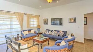 A living room with a sofa, chairs, a coffee table, and a ceiling light fixture.