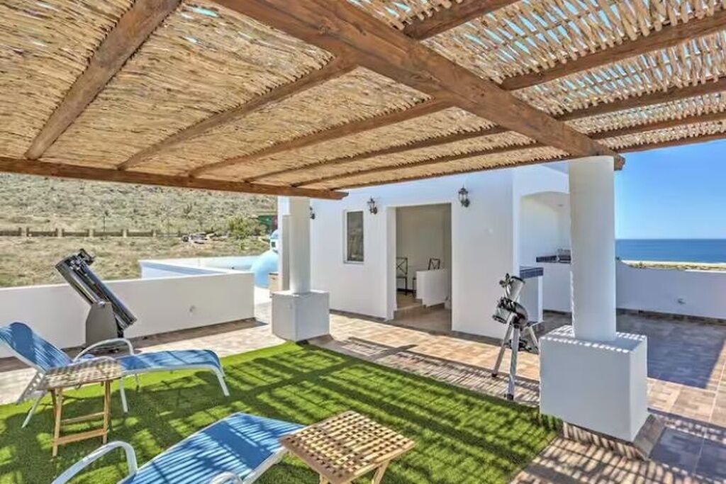 Un espace extérieur abrité comprenant une piscine, des chaises longues et une vue sur la mer.