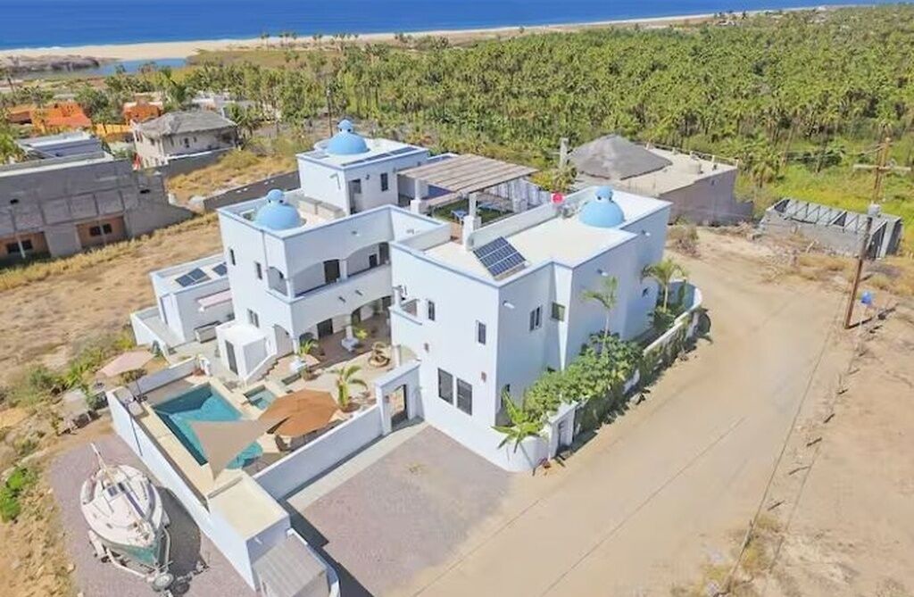 Un bâtiment moderne de couleur blanche, doté de coupoles bleues, d’une piscine et offrant une vue sur l’océan.