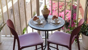 A round table with a vase, two cups, and two pastries on a balcony with chairs. - Spacious 3-bedroom beachfront apartment (Pozzallo)