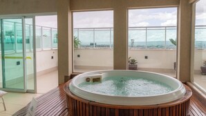 Ein Whirlpool in einem Raum mit großen Fenstern, Holzboden und Blick auf die Stadt.