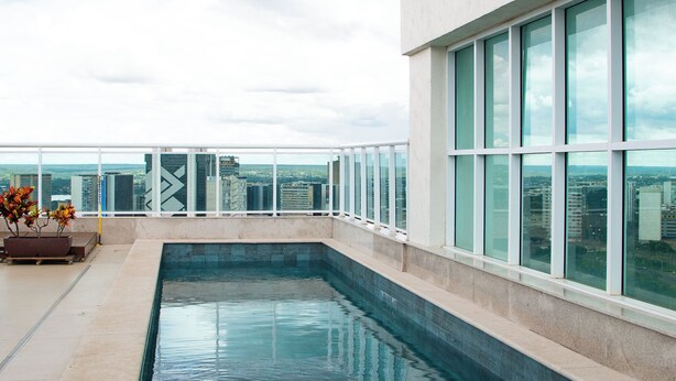 Ein Pool auf dem Dach mit Blick auf die Stadt, großen Fenstern und einem Blumentopf.