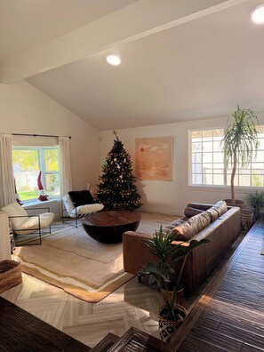 A modern living room with a Christmas tree, a sofa, a coffee table, and a large window. - Spacious family home 5min to beach + freeway, perfect for kids + entertaining (Solana Beach)
