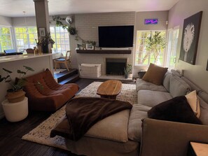 A living room with a fireplace, a sofa, a chair, and a television. - Spacious family home 5min to beach + freeway, perfect for kids + entertaining (Solana Beach)
