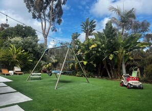 Ein Garten mit Schaukel, kleiner Spielzone und Spielzeugauto.