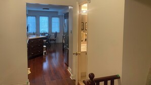Un corridoio che conduce a una sala da pranzo con cucina, con frigorifero e bagno visibili attraverso una porta aperta.