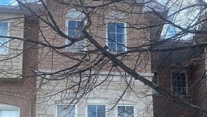 Una casa a due piani con garage, facciata in pietra e numerose finestre.