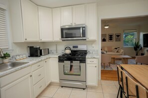 A kitchen with white cabinets, a microwave, a stove, and a sink.