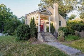 A single-story house with a red door, a front porch, and a stone staircase leading to the entrance. - Bright & Cozy 2BR w/ Yard – Private Entrance In Silver Spring (Silver Spring)