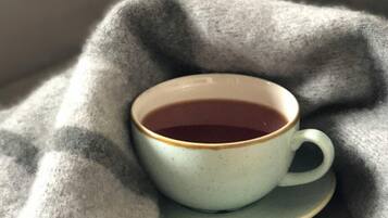 A cup of tea on a saucer placed on a textured grey blanket.
