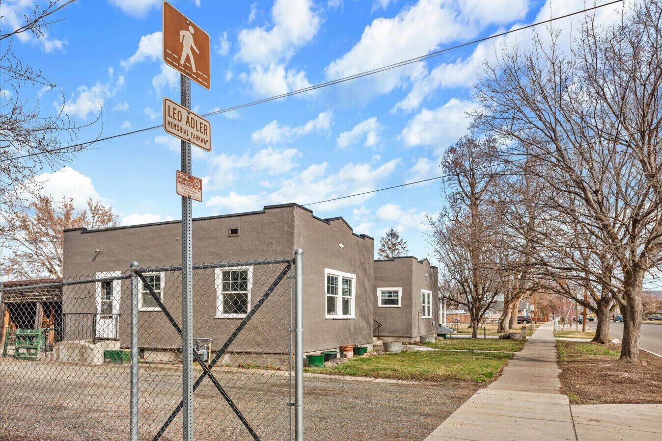 A building with a pedestrian crossing sign, a chain-link fence, and a clear sky.