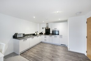 A modern kitchen with white cabinets, a microwave, a stove, and a built-in oven. - Aspire Residence Suite - Grampian Lettings (Aberdeen)