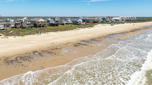 Ein Hotel direkt am Strand mit mehreren Ebenen, einem Sandstrand und Wellen.