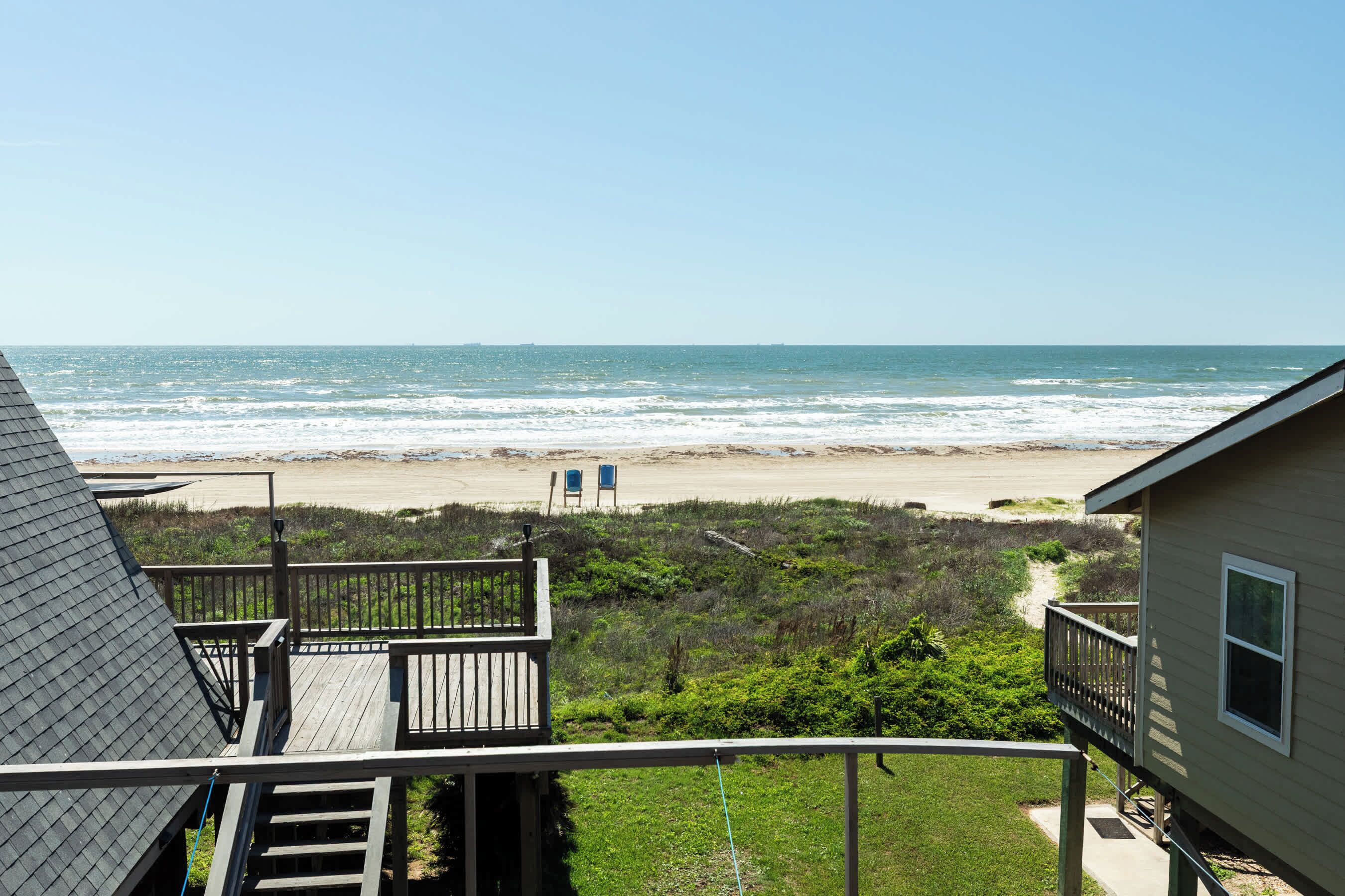 Vista a la playa desde un balcón con terraza y una casa.