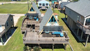 Ein Strandgrundstück mit mehreren Holzhäusern, darunter ein Haupthaus und einige kleinere Hütten, die durch eine Holzterrasse verbunden sind.
