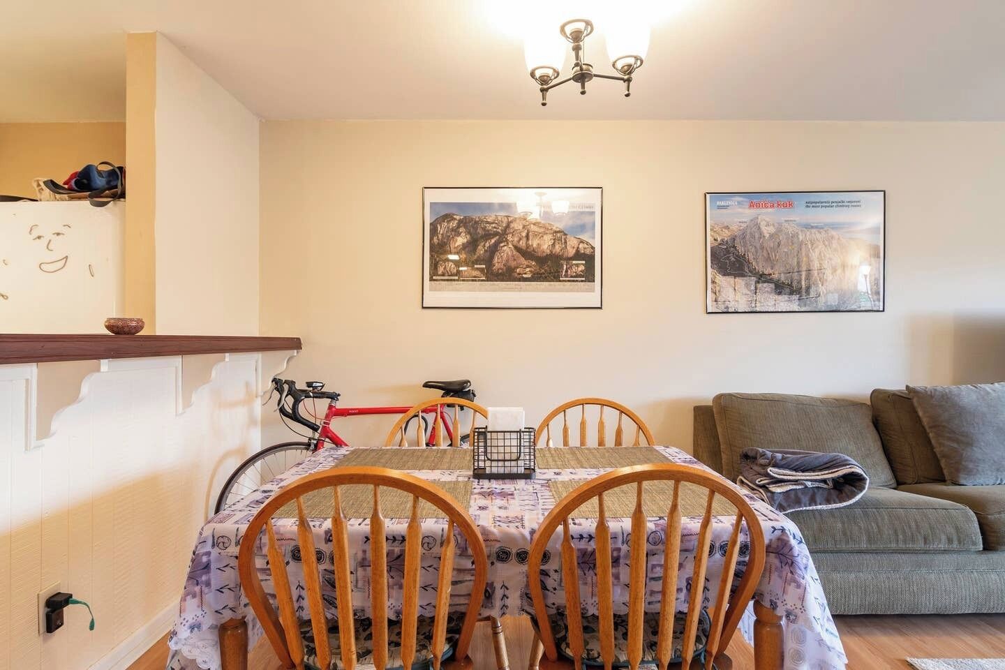 Una zona de menjador amb taula preparada per a quatre, una bicicleta i un sofà al fons.