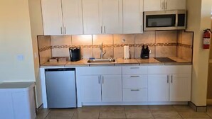 A compact kitchen with white cabinets, a microwave, a dishwasher, and a tiled backsplash. - Casita Sol en el Dorado Rach para parejas/Starlink Wifi/Spa (B.C.)