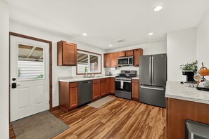 A modern kitchen with wooden cabinets, stainless steel appliances, and a marble countertop.