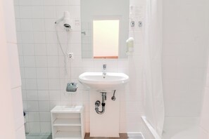 A bathroom with a white sink, a mirror, a shower, and a toilet. - Atrium Hotel Salzburg (Salzburg)