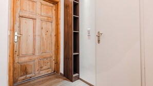 Una puerta de madera con manija metálica, una pared blanca y un suelo de madera.