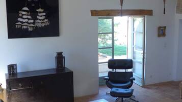 Un salon spacieux avec une grande fenêtre, un canapé noir, une table basse blanche et un luminaire suspendu.