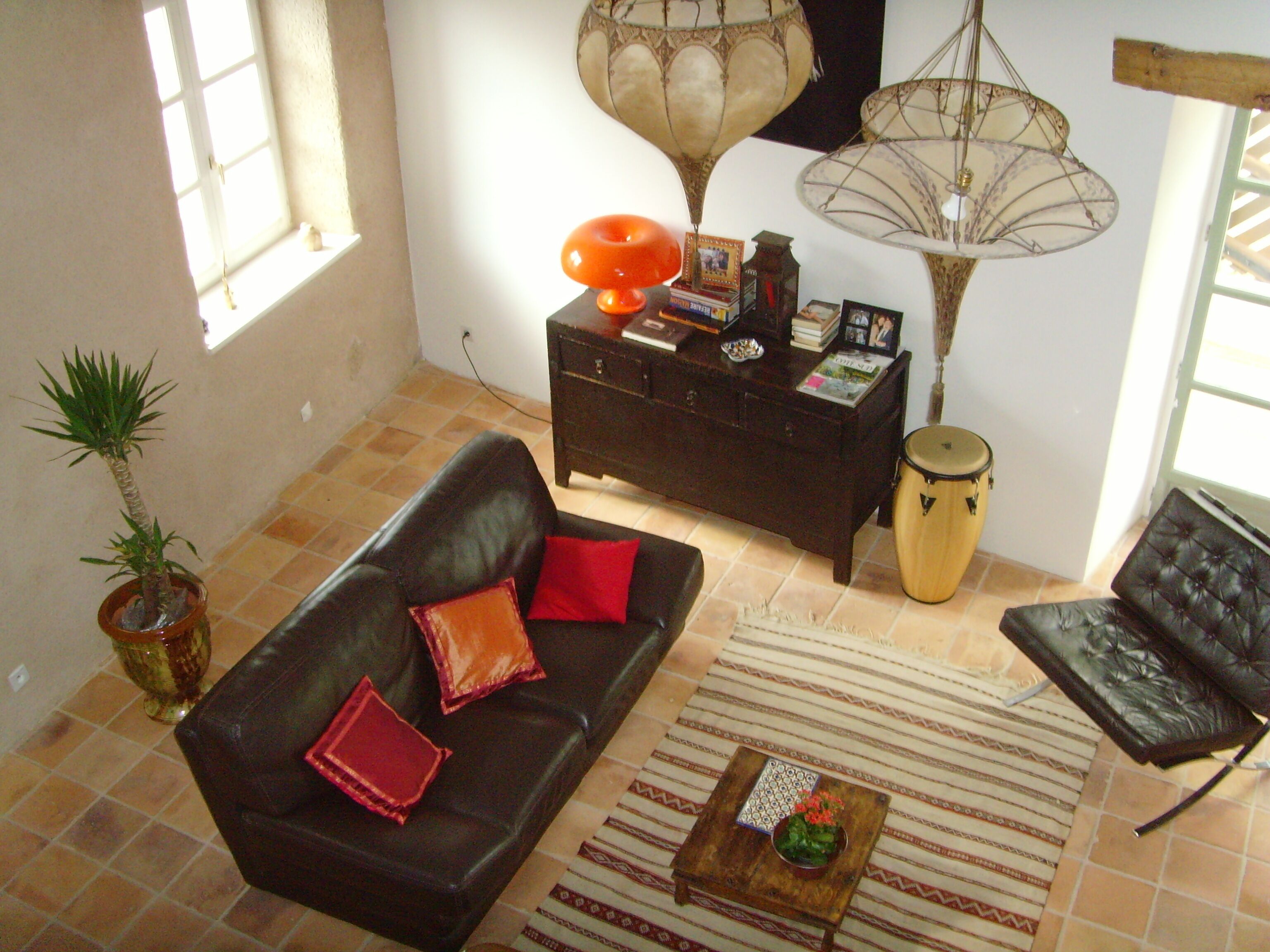 Uma sala de estar com sofá, mesa de centro, luminária, um tambor e planta em vaso.