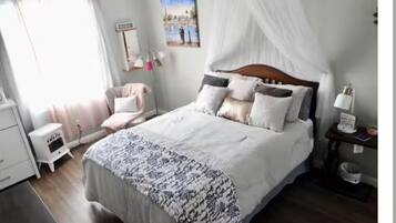 Ein Schlafzimmer mit Bett, Nachttisch, Stuhl und einem Bild an der Wand.