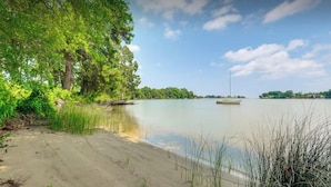 Un lac paisible aux rives sablonneuses, entouré d’une végétation luxuriante et verdoyante, sous un ciel dégagé.