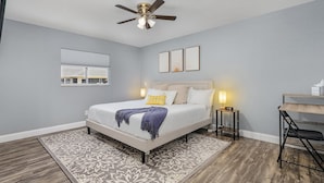 A bedroom with a bed, bedside tables, a ceiling fan, a rug, and a desk. - New Enclosed Pool, Family Friendly Oasis (Cape Coral)