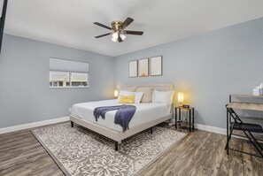 A bedroom with a bed, bedside tables, a ceiling fan, a rug, and a desk. - New Enclosed Pool, Family Friendly Oasis (Cape Coral)